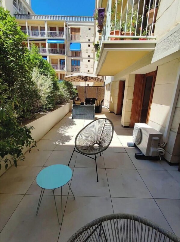 A courtyard with outdoor seating, a fan, and a small table.