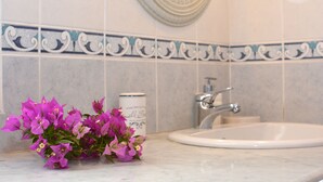 A bathroom with a white sink, a mirror, and decorative tiles. - THE COTTAGE (Nisaki)