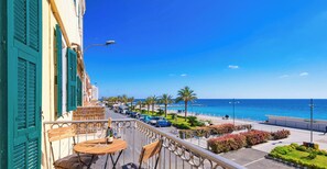 A balcony with a table, chairs, and a bottle of champagne.