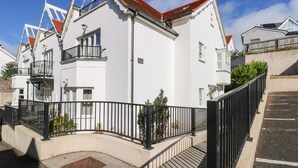 Un edifici blanc amb teulada vermella, un balcó i una entrada tancada per una reixa.