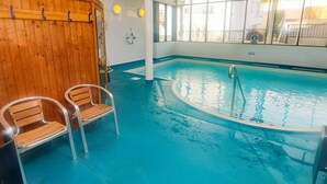 Una piscina interior amb bancs de fusta i una vista despejada de l'exterior a través de grans finestres.