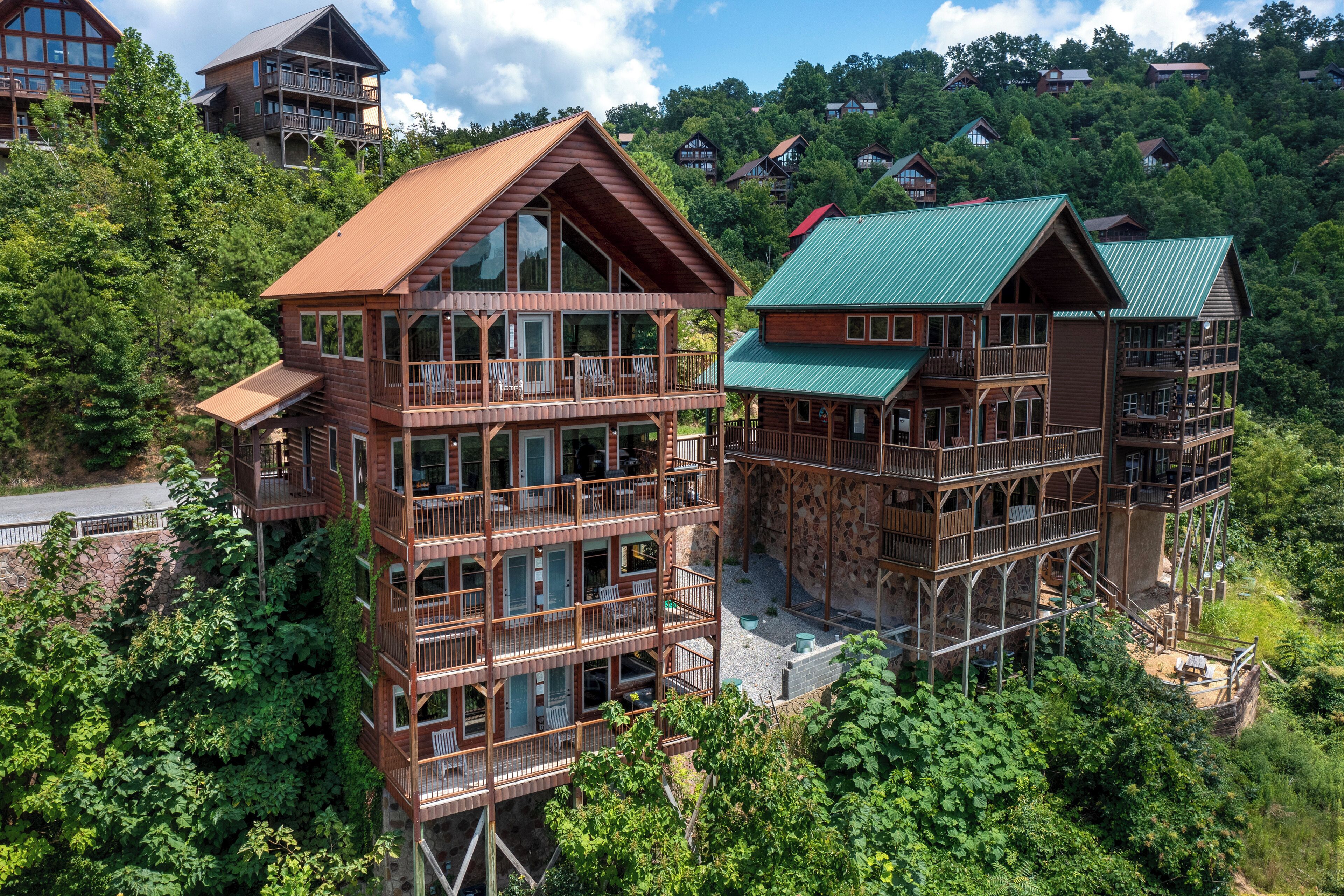 A multi-story log cabin with balconies and large windows, surrounded by dense forest.