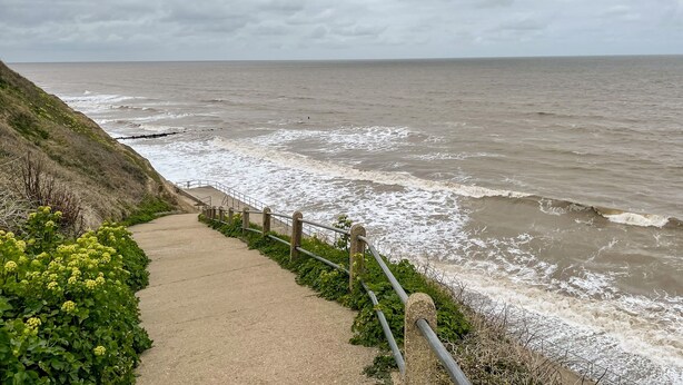 A coastal walkway with a railing, leading to the sea. - Coral House (Cromer)