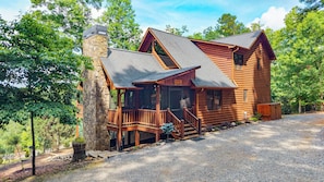 A log cabin with a stone chimney, a porch, and a gravel driveway. - Soaring Hawk Lodge - Morganton, GA (Morganton)