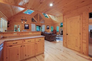 Interior de una cabaña de madera con cocina, comedor y sala de estar.