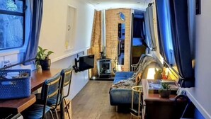 Ett kompakt bostadsutrymme med ett litet kök, en sittgrupp med soffa och fåtöljer, ett litet bord och en tv.