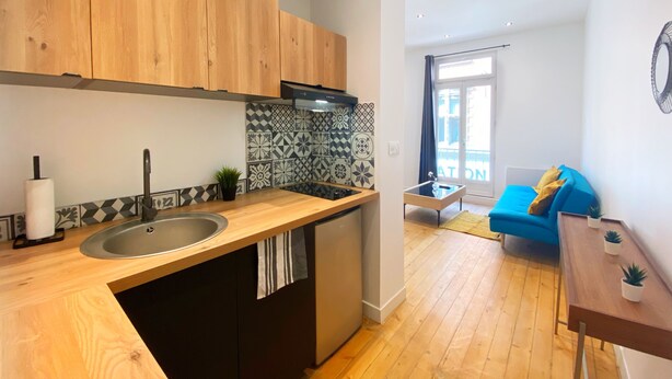 Una cocina moderna con armarios de madera, un grifo negro y un salpicadero azulejado.