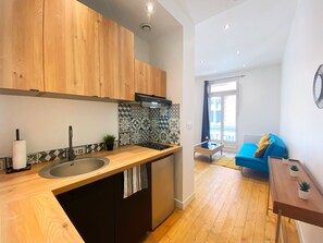 A modern kitchen with wooden cabinets, a black faucet, and a tiled backsplash. - Toulouse Hypercentre 2: Beautiful, furnished, and air-conditioned apartment (Toulouse)