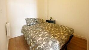 Un dormitorio con cama, mesita de noche y planta en maceta.