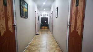 Un corridoio con piastrelle a motivi decorativi, porte in legno con pannelli ornamentali e una plafoniera.