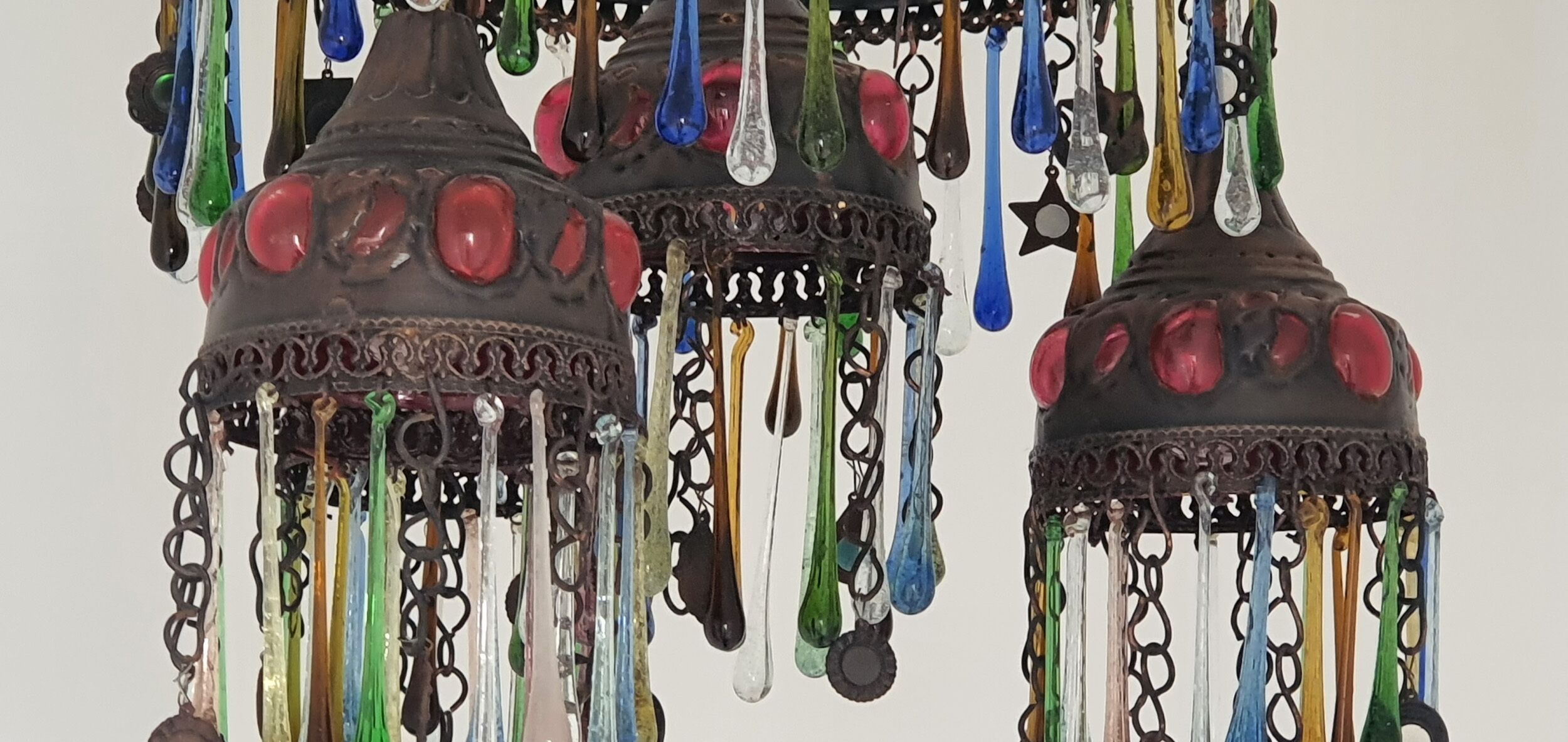 Un candelabro con varios niveles y elementos de vidrio de colores.