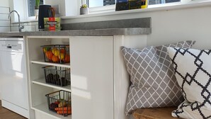 Una cocina con armarios blancos, lavavajillas integrado y un ventanal sobre el fregadero.