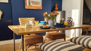 Un comedor con una mesa de madera, sillas de mimbre y cojines a rayas.