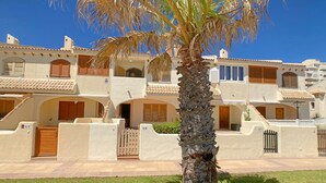 Un edificio a più piani con uno stile architettonico tradizionale mediterraneo, caratterizzato da pareti in stucco, tegole in terracotta e persiane in legno.