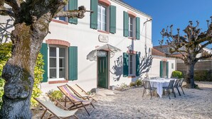 A two-story building with a white facade and green shutters. There is a sign above the door that reads "Villa Nizza."