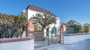 A two-story building with a gated entrance, brick walls, and a tree in front.