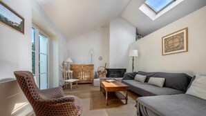 A living room with a sofa, armchair, wooden coffee table, and a fireplace.