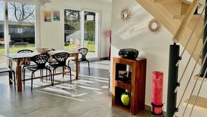 A modern interior with a dining area, staircase, and a view of the outdoors. - Villa Rubis, an ecological house with modern comfort (Varengeville-sur-Mer)