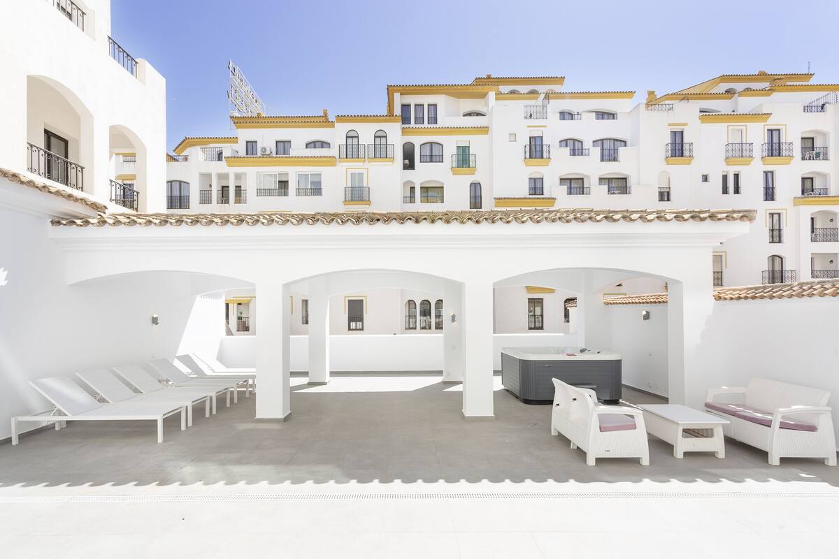 Un patio con sillones blancos, una bañera de hidromasaje y un juego de sofá blanco.