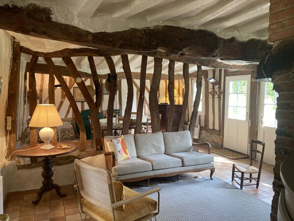 A rustic room with exposed wooden beams, a sofa, a chair, a lamp, and a small table.