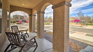 Un patio cubierto con vistas a una calle residencial, que cuenta con un techo de hormigón y columnas de piedra.