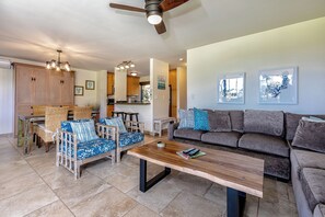 Ein geräumiger Wohnbereich mit Couch, Korbsesseln und einem Holztisch.