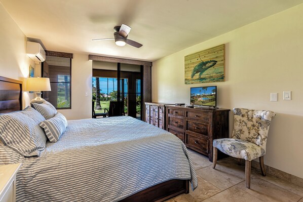 A bedroom with a large bed, a ceiling fan, a TV, a wooden cabinet, and a chair.