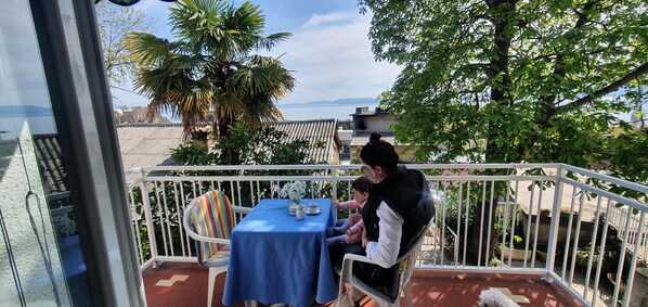 A balcony with a table and chairs, overlooking a scenic view with trees and a distant landscape.