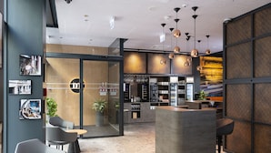 A modern interior with a reception desk, seating area, and kitchen visible. - Three Corners Downtown Hotel (Budapest)