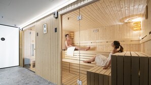 A sauna with wooden walls and benches, a glass door, and a tiled floor. - Three Corners Downtown Hotel (Budapest)