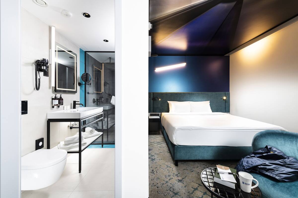 Une chambre d’hôtel moderne comprenant une salle de bain, un lit et un coin salon.
