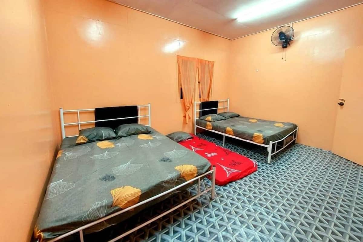 A room with two beds, a ceiling fan, and a patterned floor.