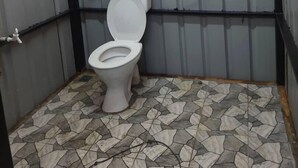 A small, enclosed bathroom with a toilet, a shower, and a wall-mounted water heater.