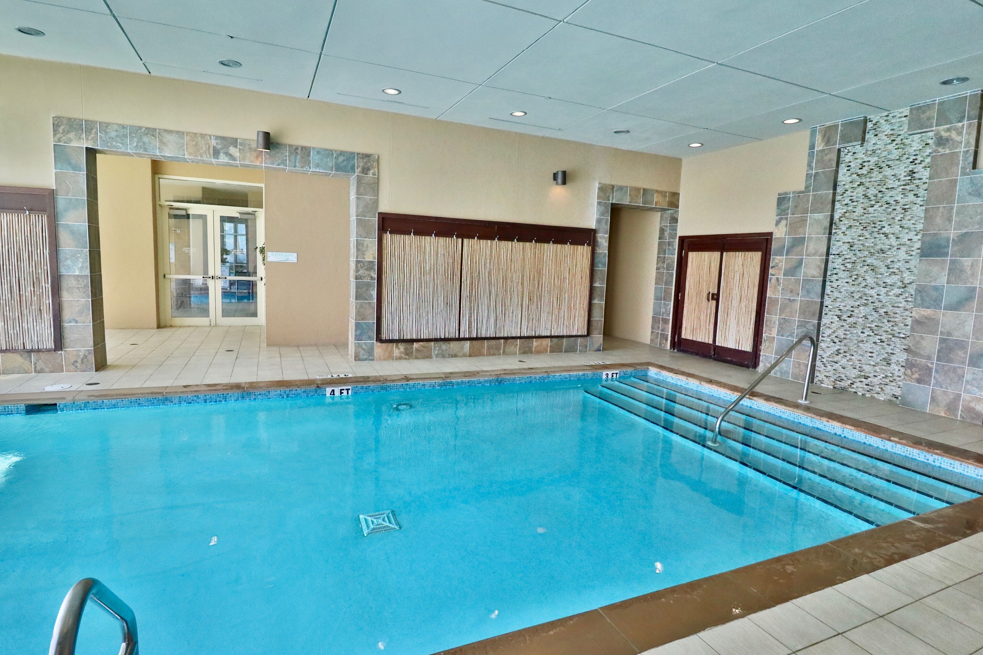 Una piscina interna con acqua cristallina, pareti piastrellate e pavimento in piastrelle.