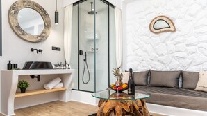A modern bathroom with a glass shower enclosure, a round mirror, and a glass table with a wooden base.
