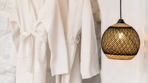 Two white robes hanging on a wooden rack against a stone wall.