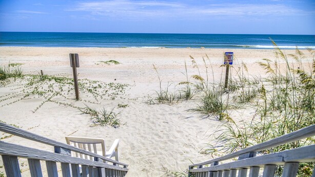 A beach view with a wooden staircase leading down to the sand, a sign that reads "KEEP OFF DUNES," and a clear blue sky. - 7 Bed, 7.5 Bath, Oceanfront Home, Private Pool that can be heated (Garden City Beach)