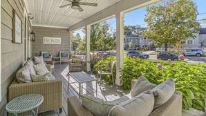 A covered porch with wicker furniture, a table, and a sign that reads "BEACH". - You Are My Sunshine (South Haven)