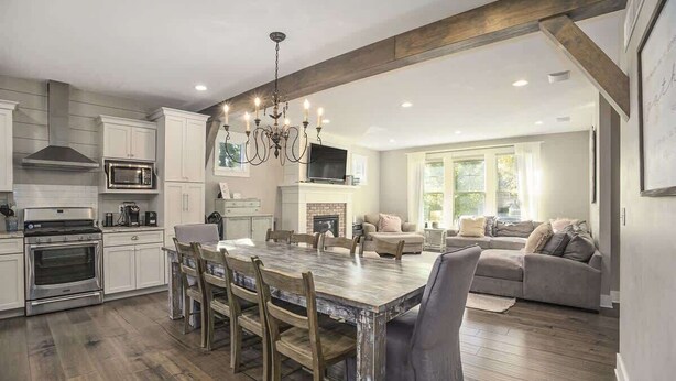 A modern kitchen with white cabinetry, a dining table, and a chandelier. - You Are My Sunshine (South Haven)