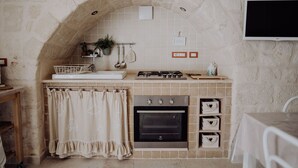 Una cocina compacta con un arco de piedra, estufa a gas, horno y un estante pequeño con adornos.