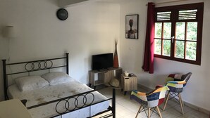 Et soveværelse med seng, fjernsyn, stol og et vindue med gardiner.