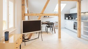 Une cuisine moderne avec des armoires blanches, un plan de travail noir et des poutres en bois.