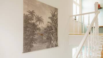 A staircase with white balusters and a handrail, leading to a landing with a large framed botanical illustration on the wall.