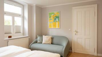 Un dormitorio con cama, sofá, radiador, ventana y puerta.