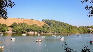 A calm lake with several boats anchored, surrounded by lush green hills and a clear blue sky. - Waters Reach (Kingsbridge)