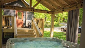 Een hottub in een houten terras, met uitzicht op een huis en een weg.