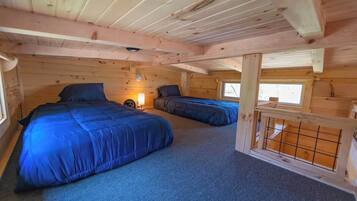 Une cabine avec deux lits, une petite table avec une lampe et une fenêtre.
