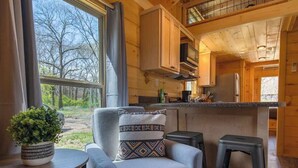 Een gezellig blokhutinterieur met een eethoek, een keuken en uitzicht op de natuur.