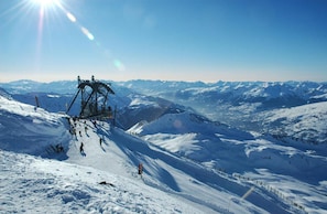 A ski lift on a snowy mountain with clear skies.