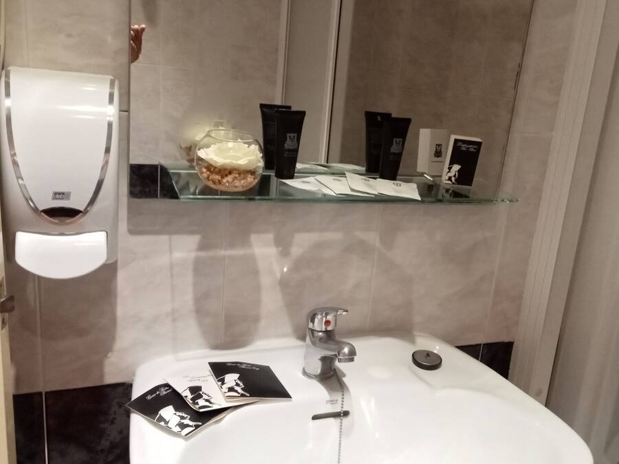 Een badkamer met een wit wastafel, een handdroger en toiletartikelen op een plank.
